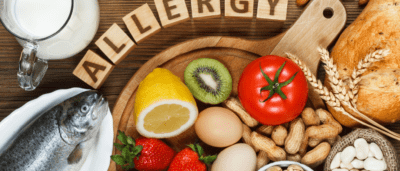 A wooden bowl of food with the word " allergy " spelled out in scrabble letters.